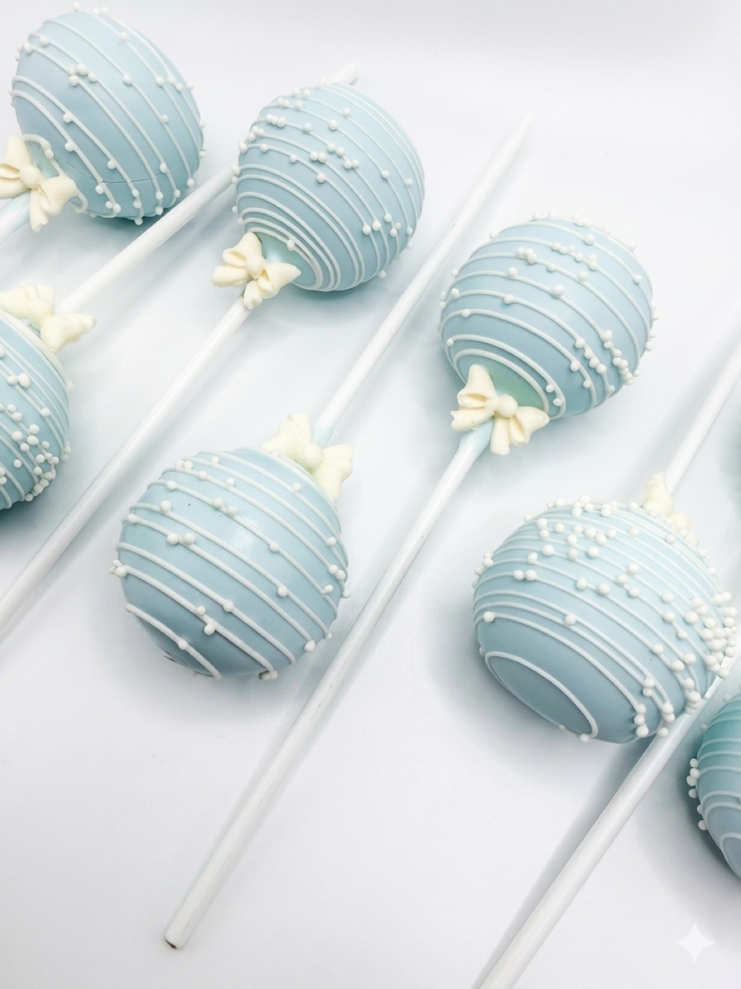 Rows of blue cake pops decorated with a delicate white bow