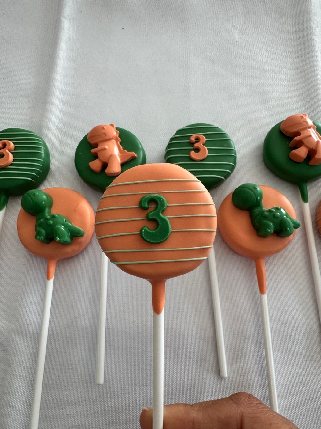 Close-up of dinosaur third birthday cake pops with number 3 and dinosaur toppers