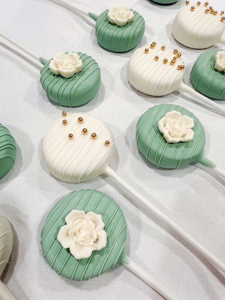 Sage green and white cake pops with a sugar rose and gold pearl details, for a wedding