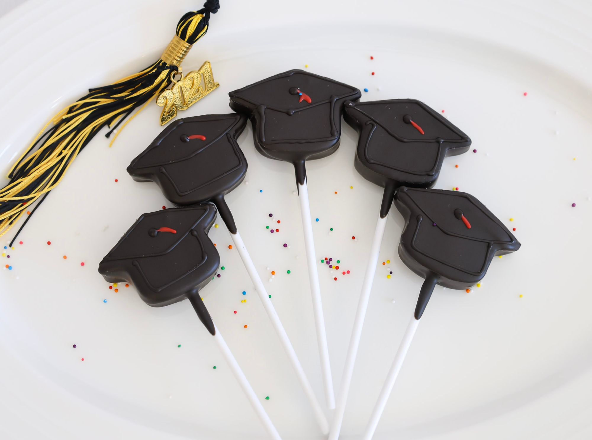 Graduation cap cake pops with a tassel charm, made for a graduation celebration