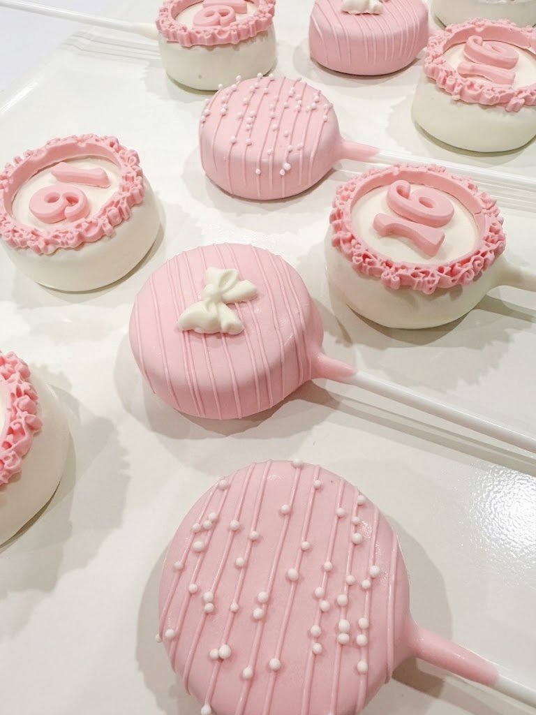 Pink Sweet 16 cake pops with a lace border and bow topper