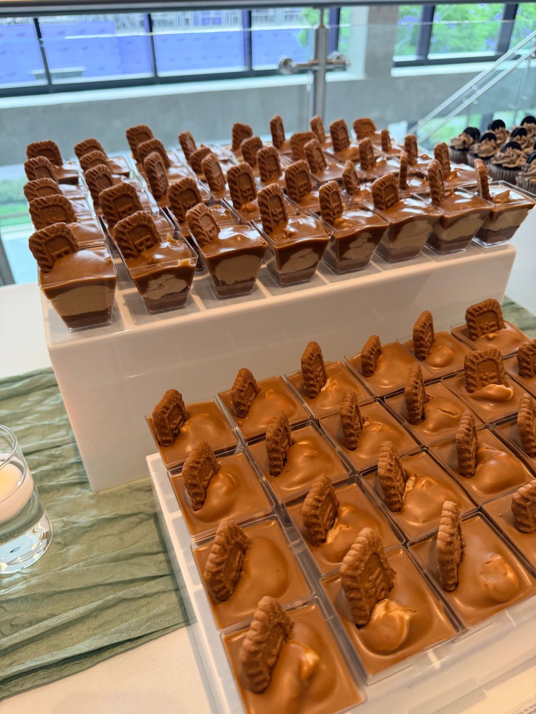 Rows of Biscoff cheesecake shooters topped with a Lotus cookie, set up for a catering display