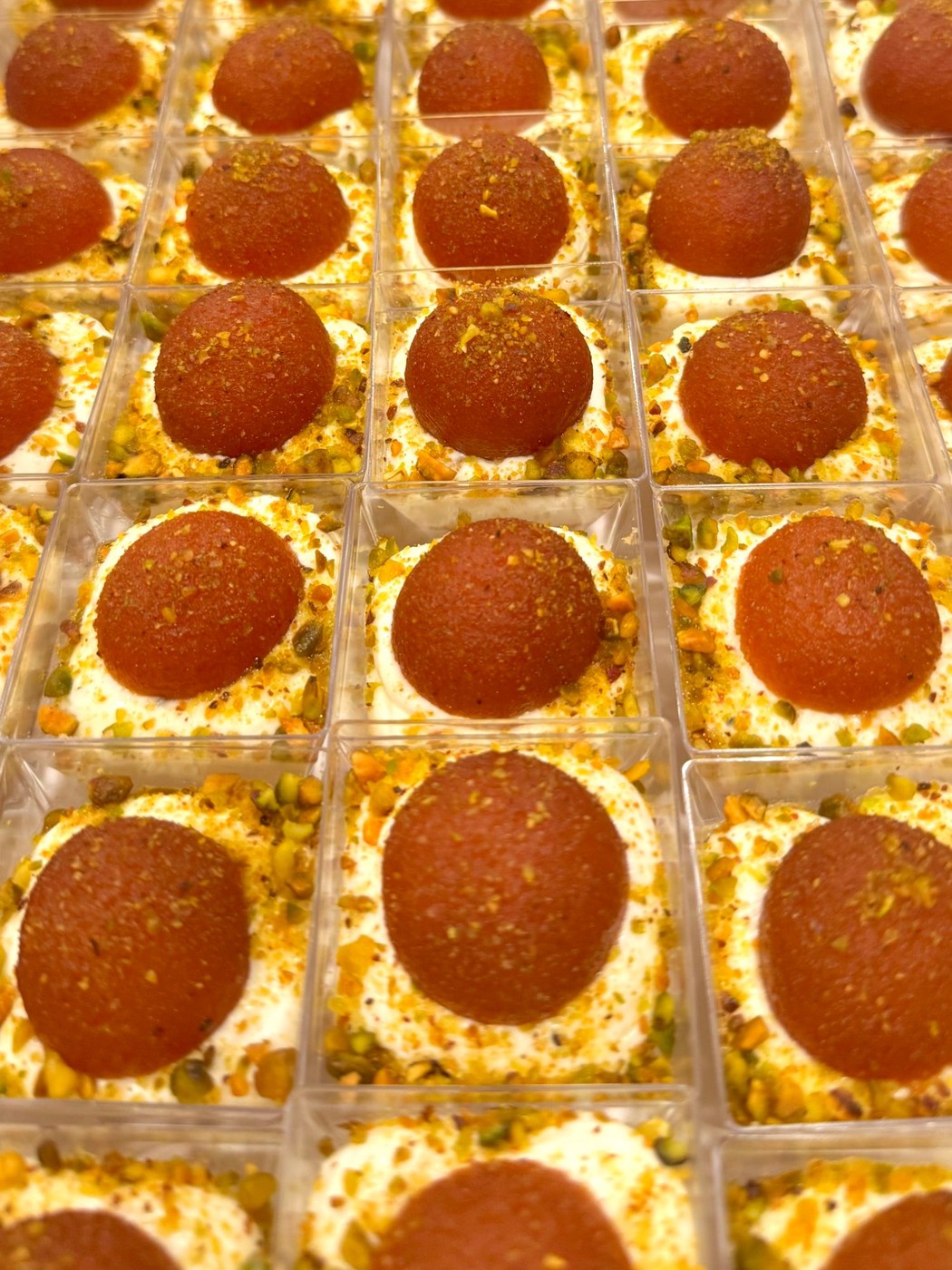 Close-up of Gulab Jamun cheesecake shooters topped with crushed pistachio
