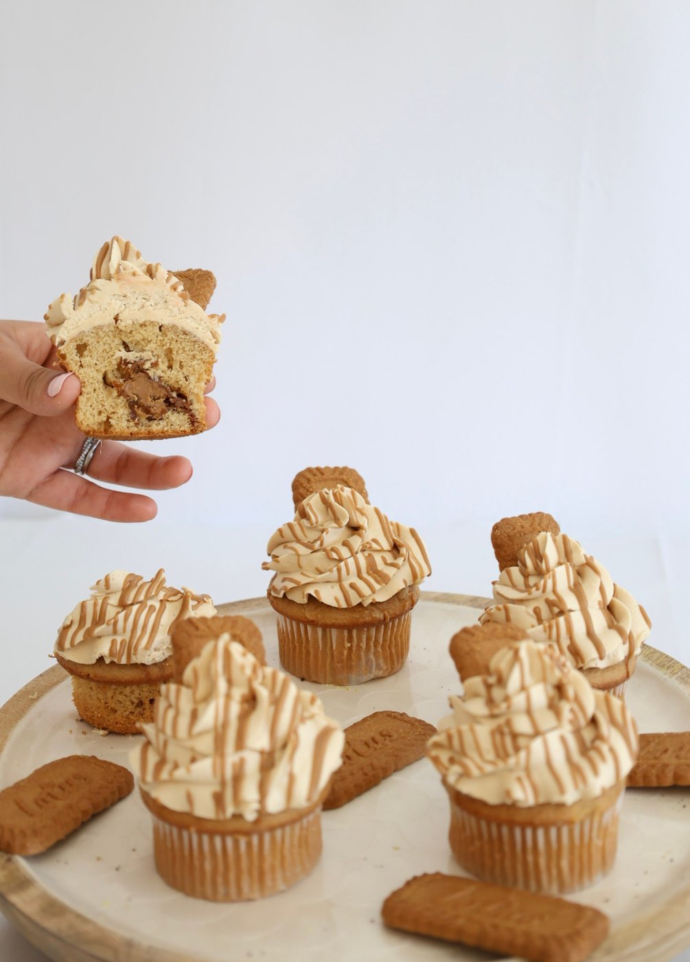 Biscoff cupcakes topped with a Lotus cookie, one cupcake cut open to show a caramel filling