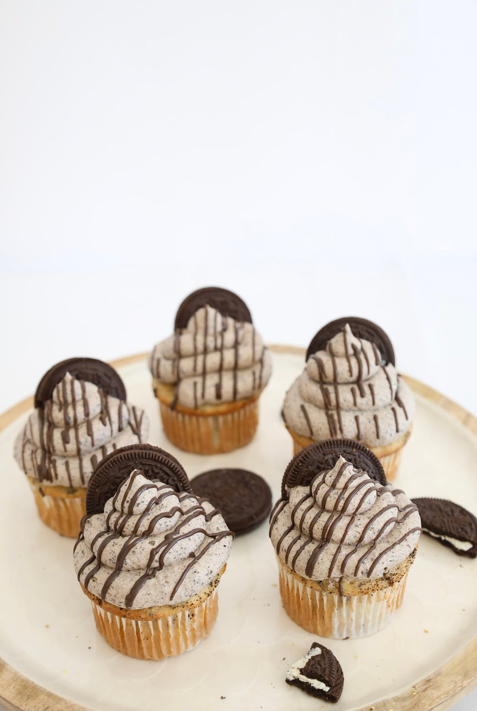 Five cookies and cream cupcakes topped with an Oreo cookie and chocolate drizzle