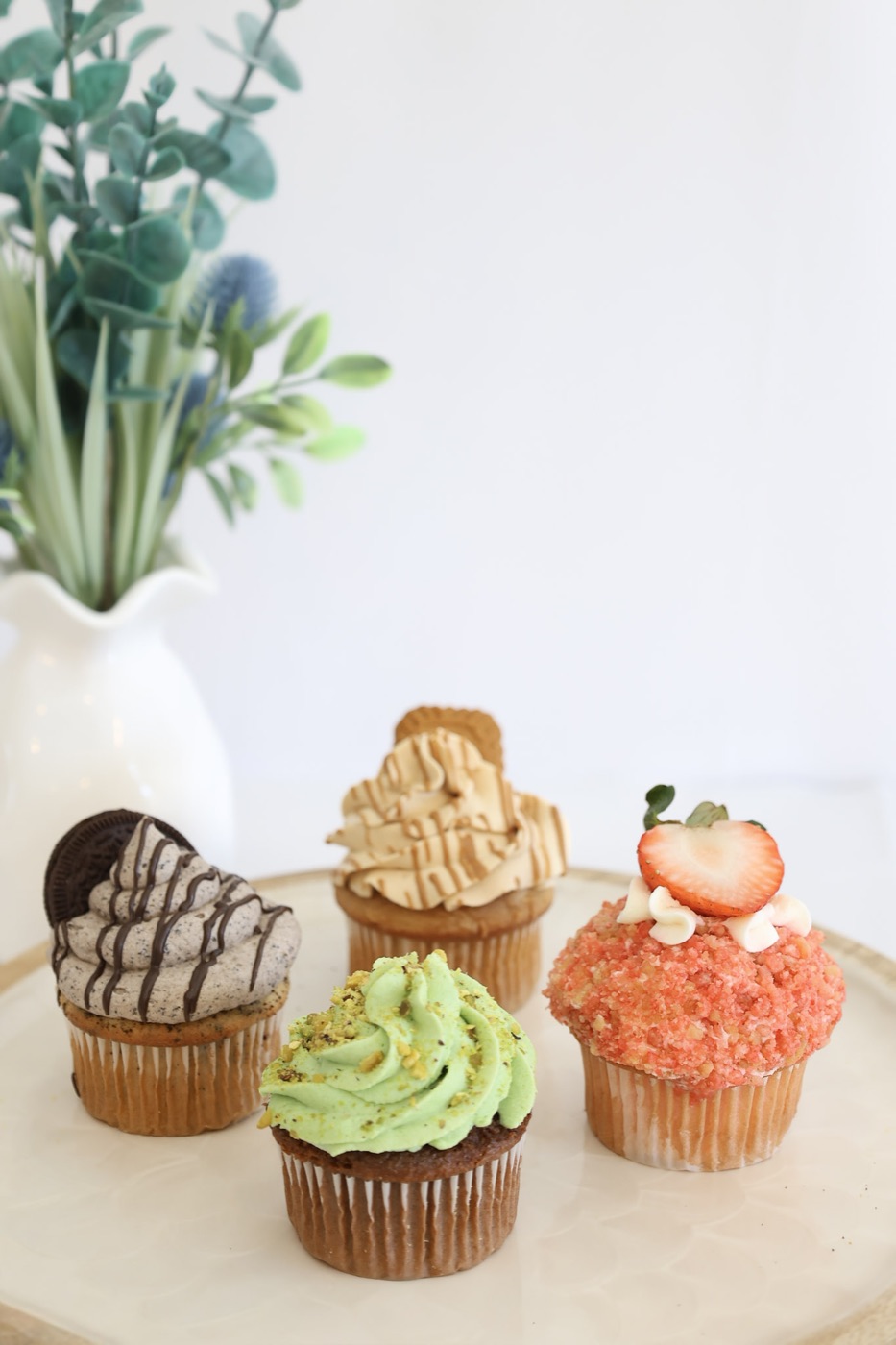 Assortment of cupcakes including cookies and cream, Biscoff, pistachio, and strawberry crunch