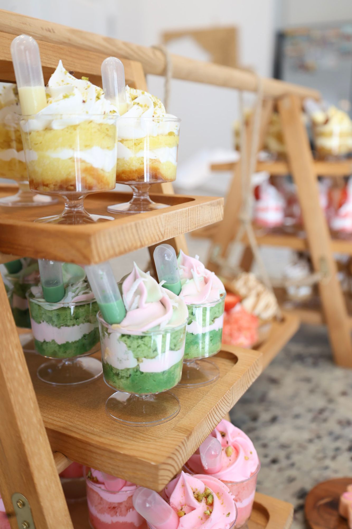 Assorted dessert cups in pistachio and matcha flavors displayed on a tiered wooden stand
