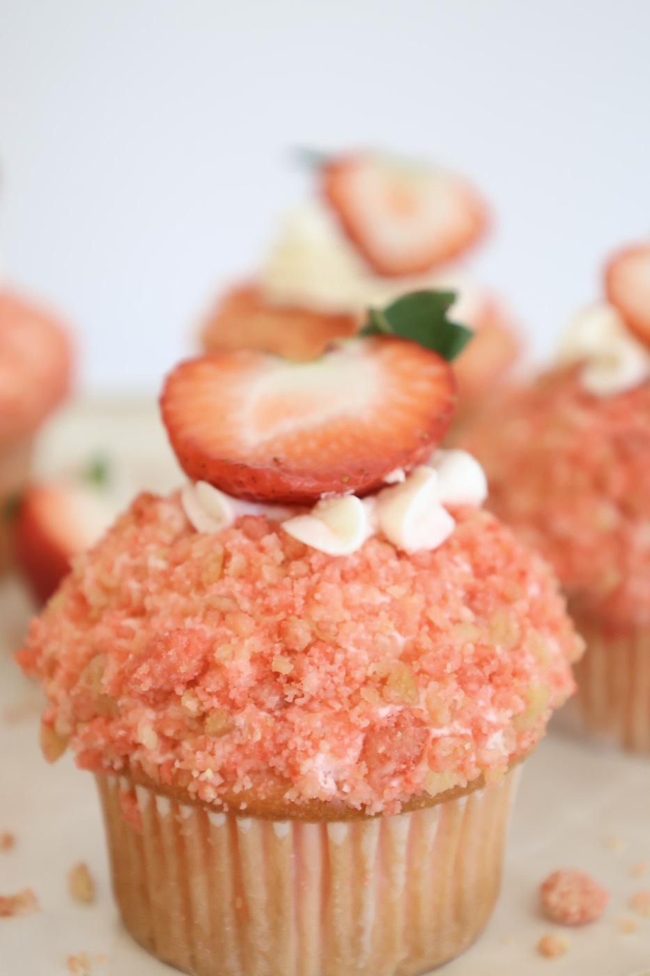 Close-up of a strawberry crunch cupcake topped with a fresh strawberry slice